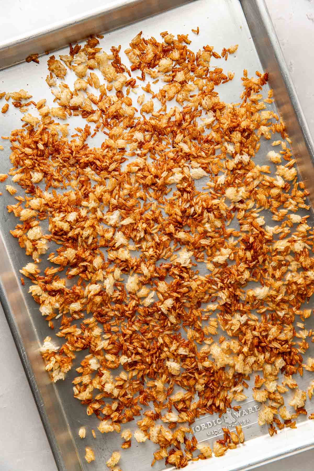 Overhead view of a sheet pan filled with freshly roasted crispy rice spread evenly over the pan. 
