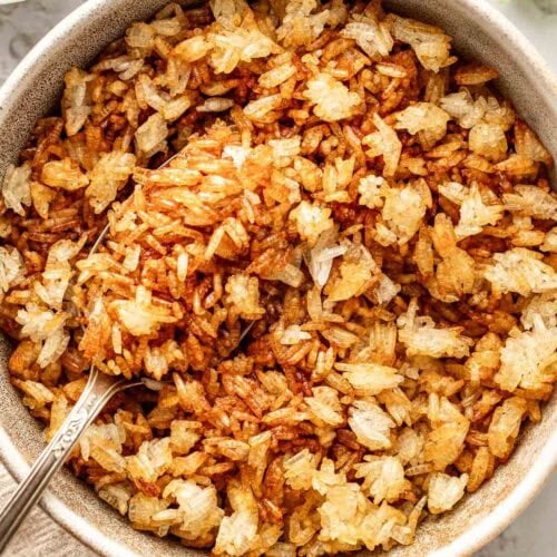Close up view of a bowl of freshly roasted crispy rice showing the browned color and crisp texure.