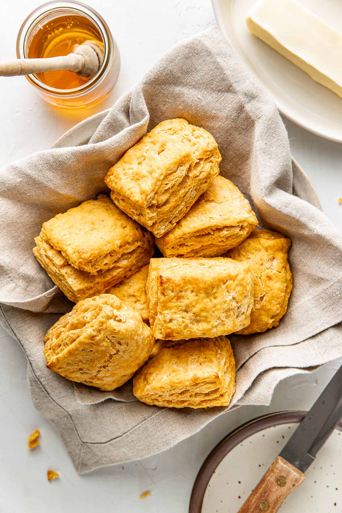 A bowl lined with a light colored linen napkin and filled with jewel-toned sweet potato biscuits.