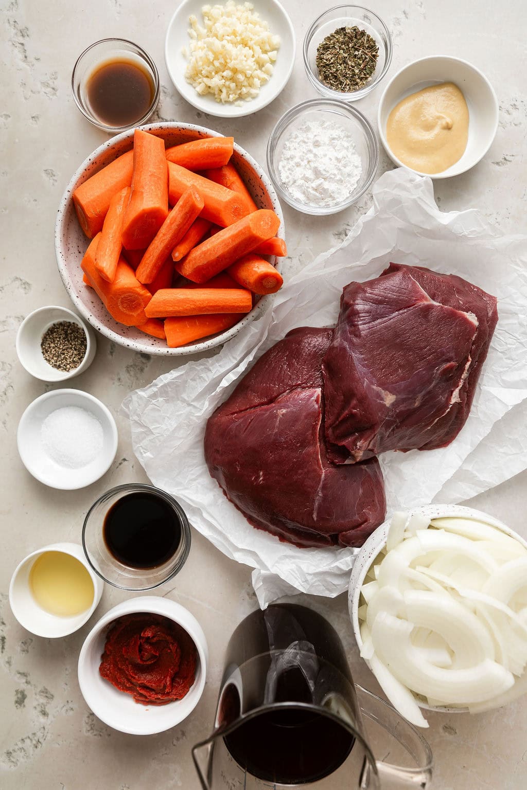 Overhead view of a variety of ingredients for Slow Cooker Venison Roast including carrots and fresh garlic. 