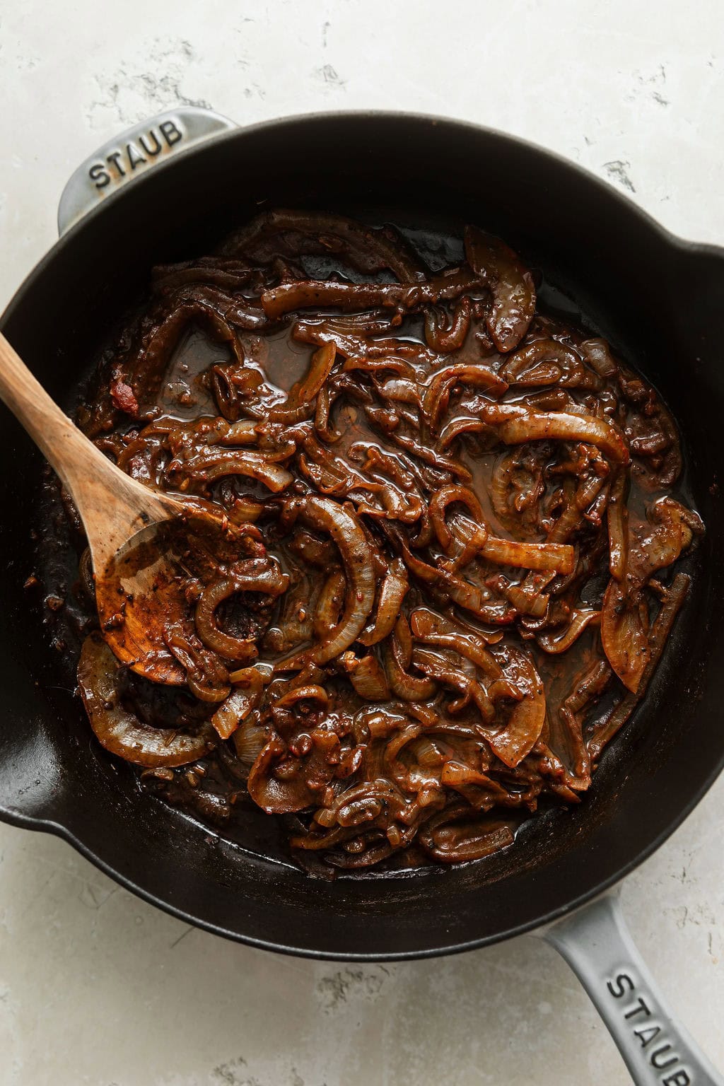 Overhead view of a black cast iron pan filled with a balsamic reduction and sliced onions. 
