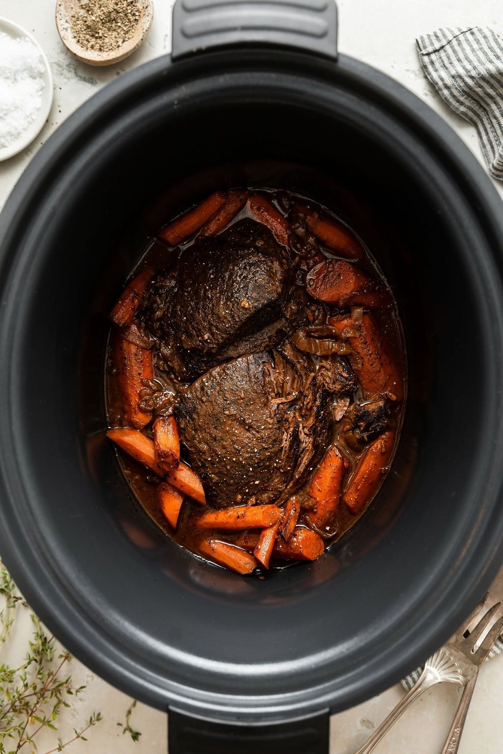 Overhead view of a slow cooker filled with venison and carrots freshly cooked and ready for plating. 