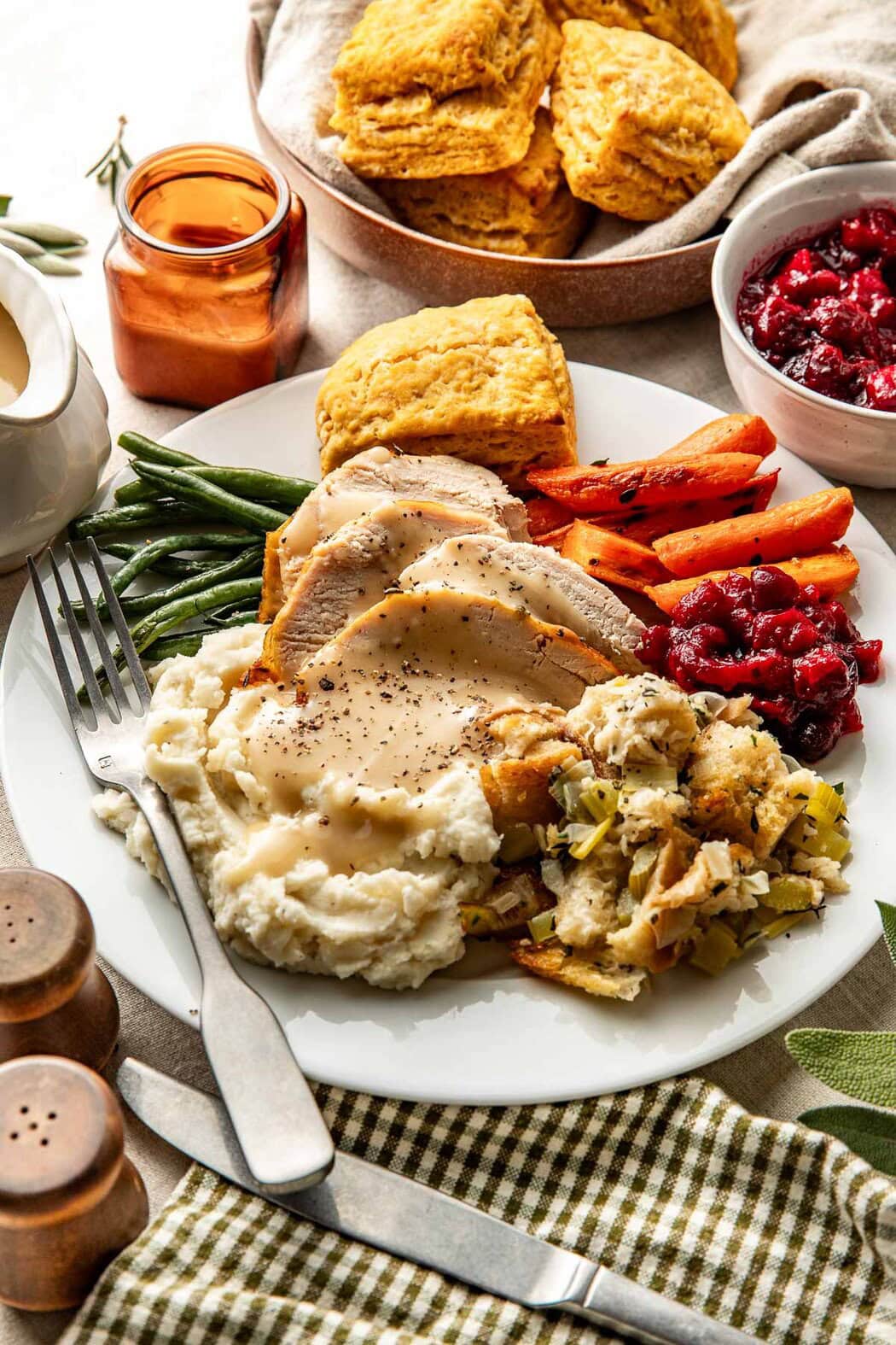 Overhead view of a plate of thanksgiving meal items including sliced turkey, gravy, mashed potatoes, and stuffing.