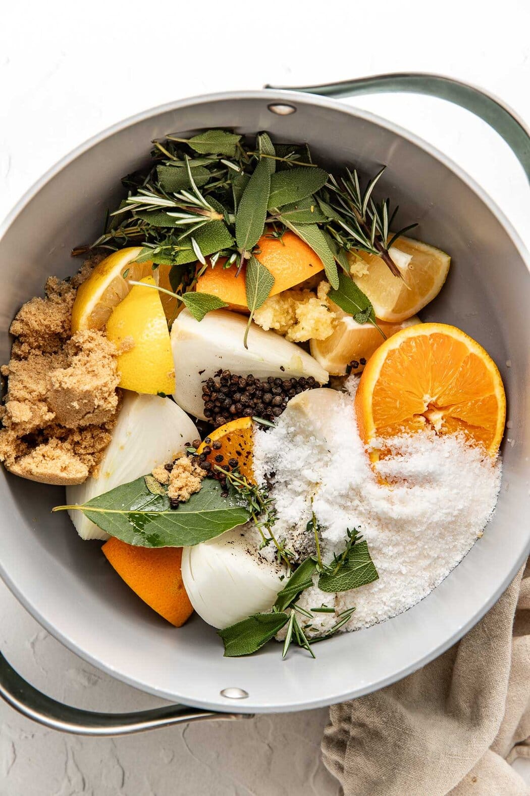 Overhead view of a pot filled with Turkey Brine ingredients including sliced lemons, onions, and herbs. 