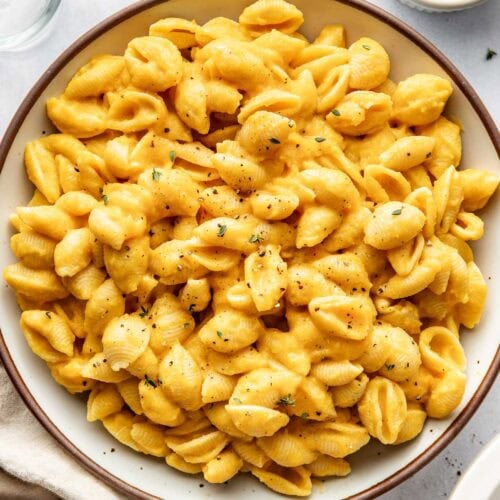 Overhead view of a ceramic bowl filled with Butternut Squash Mac and Cheese topped with black pepper.