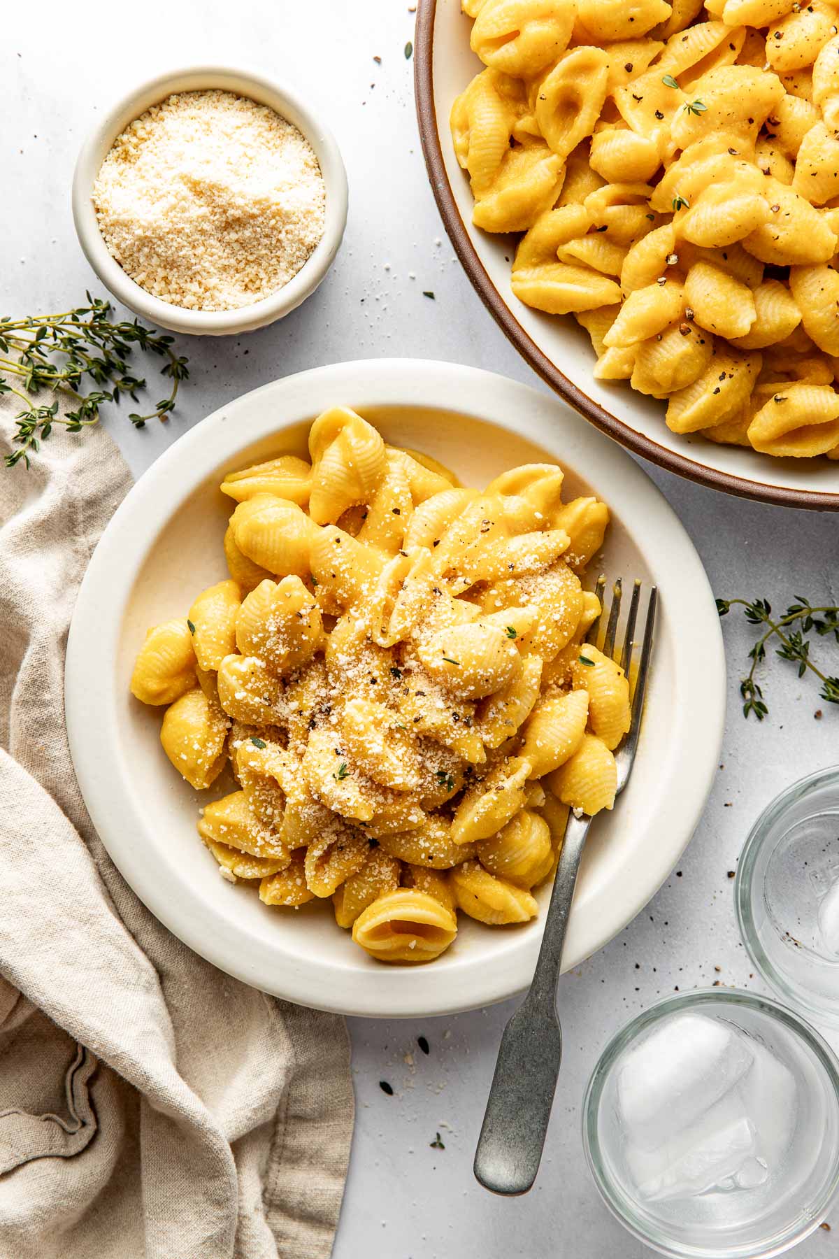 Close up view of a small white bowl of Butternut Squash Mac and Cheese sprinkled with parmesan cheese and black pepper.