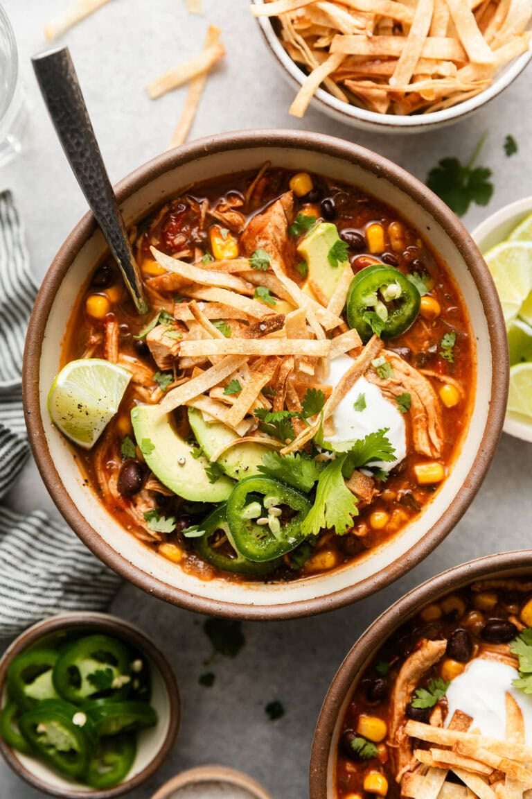 Overhead view of a bowl of chicken tortilla soup topped with cilantro and sliced avocado.