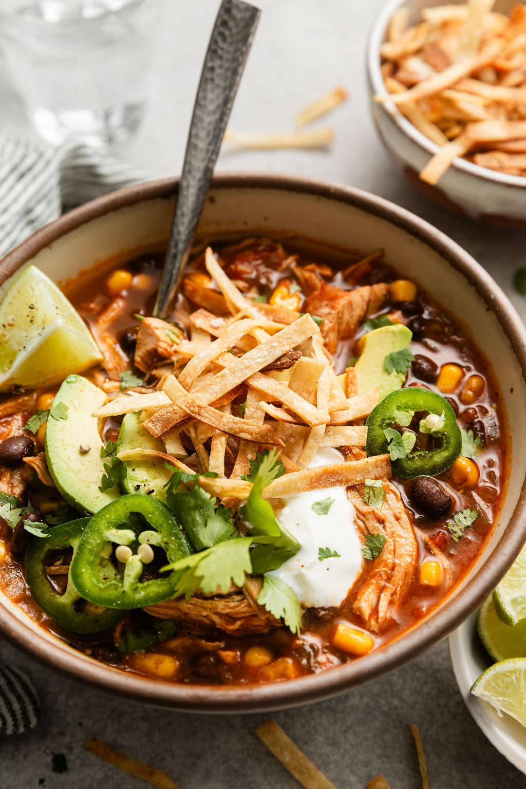 Close up view of a bowl of Chicken Tortilla Soup topped with sliced jalapenos, avocado, and a dollop of sour cream.
