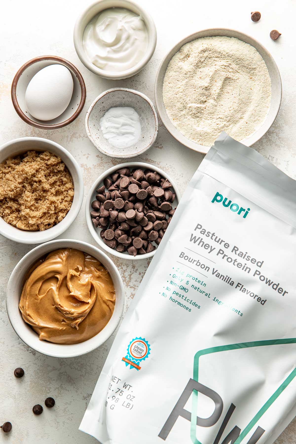 Overhead view of a variety of ingredients for Protein Cookies in different sized bowls.