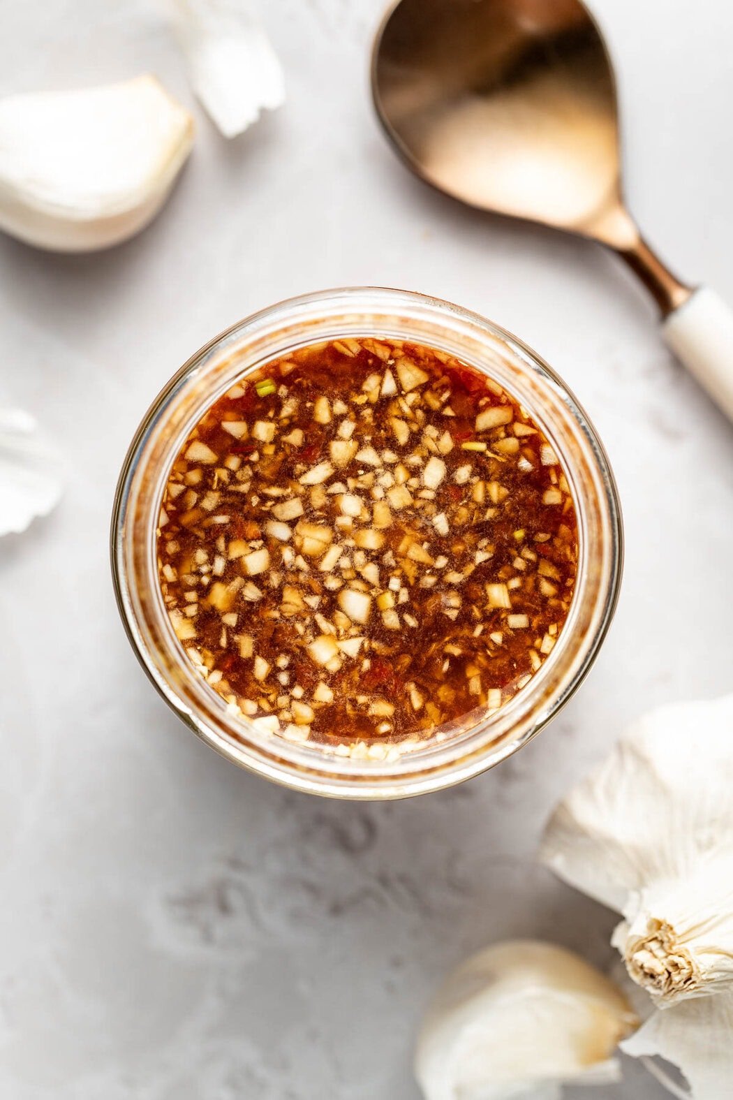 Overhead view of a glass jar filled with Stir Fry Sauce showing pieces of minced garlic on the top.