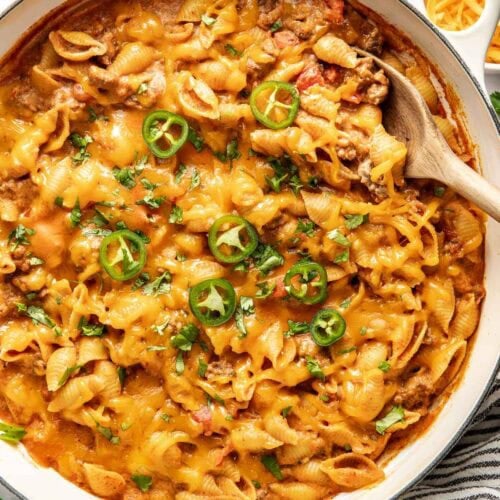 Overhead view of a white skillet filled with Taco Pasta topped with sliced jalapenos.