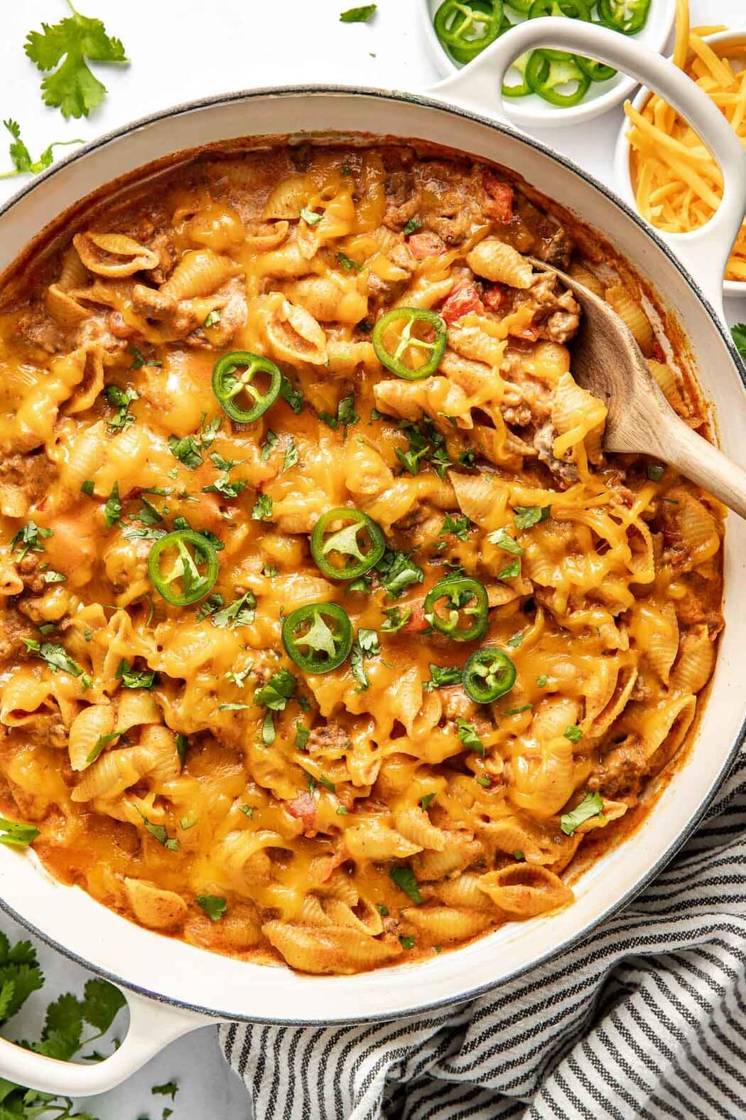 Overhead view of a white skillet filled with Taco Pasta topped with melted cheese and sliced jalapenos.