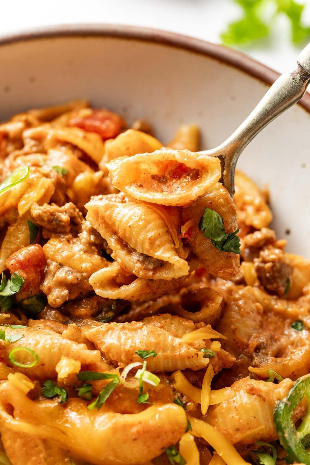 Close up view of a spoon scooping a bite of Taco Pasta topped with fresh cilantro.