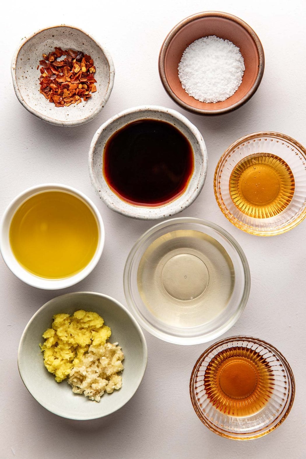 Overhead view of a variety of ingredients for Asian Salad Dressing in different sized bowls.