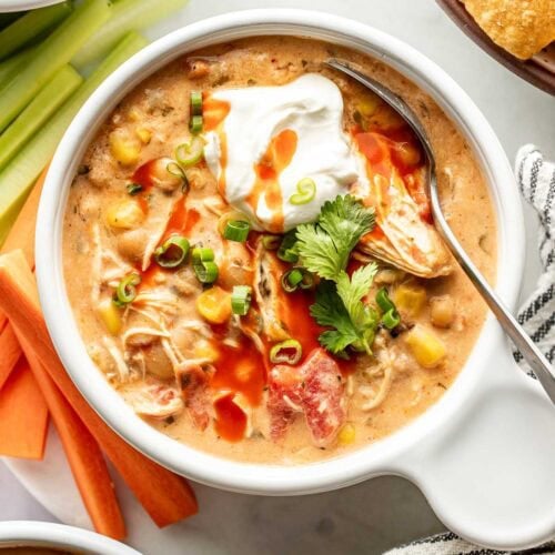 Overhead view of a bowl of Buffalo Chicken Chili topped with fresh herbs and a dollop of sour cream