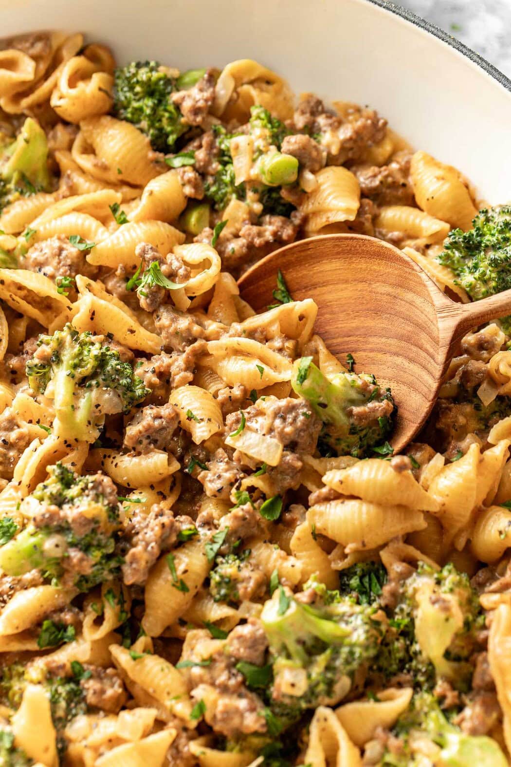 Close up view of a skillet of Homemade Hamburger Helper with a wooden spoon stirring the mixture.