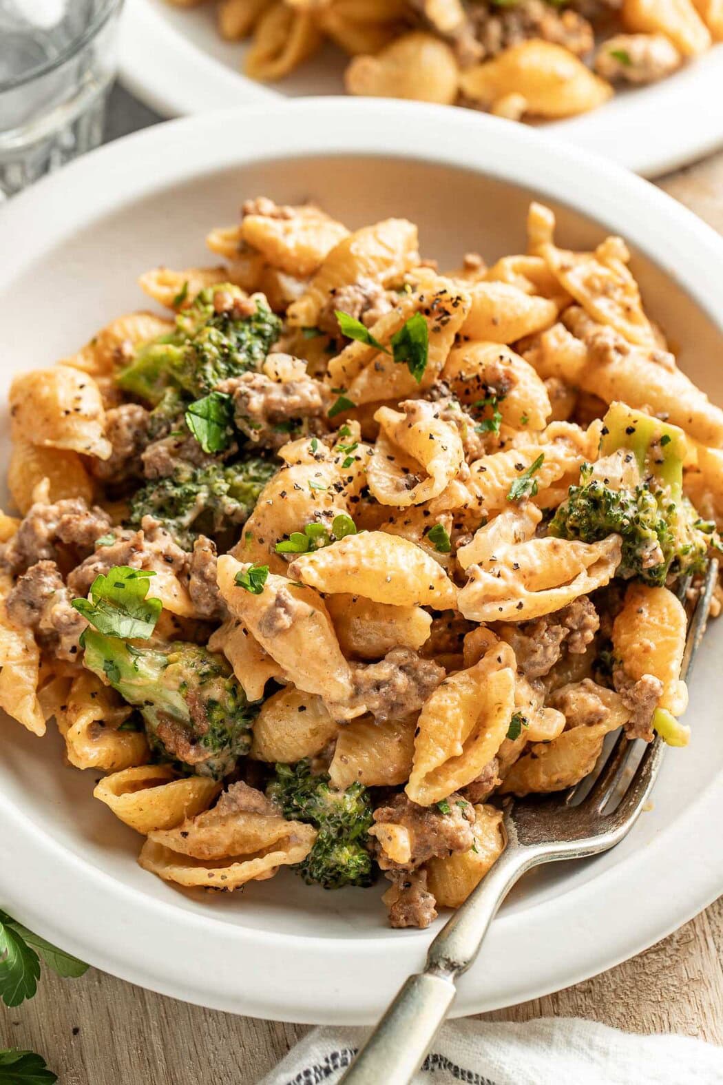 Close up view of a bowl of Homemade Hamburger Helper topped with black pepper and fresh herbs.