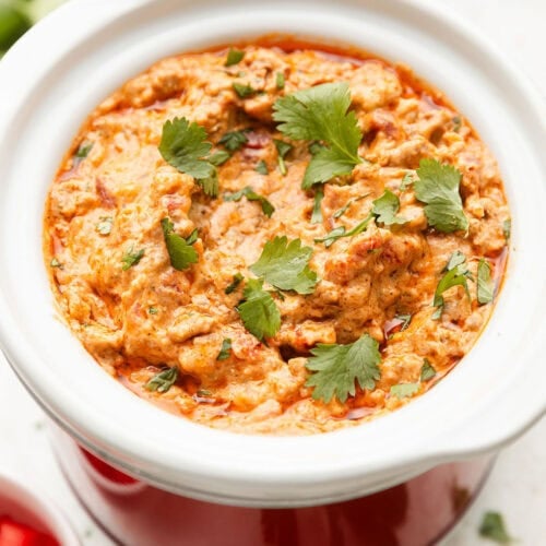 Overhead view of a slow cooker filled with Rotel Dip topped with fresh cilantro.
