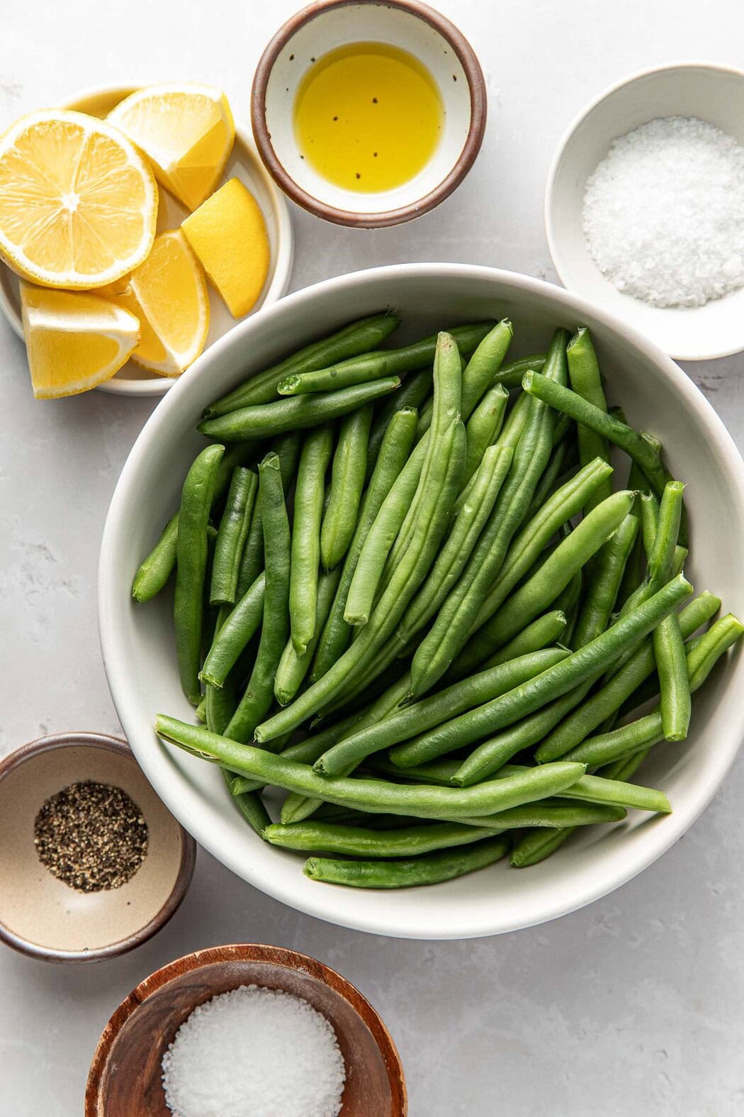 Overhead view of ingredients for Sautéed Green Beans in different sized bowls.
