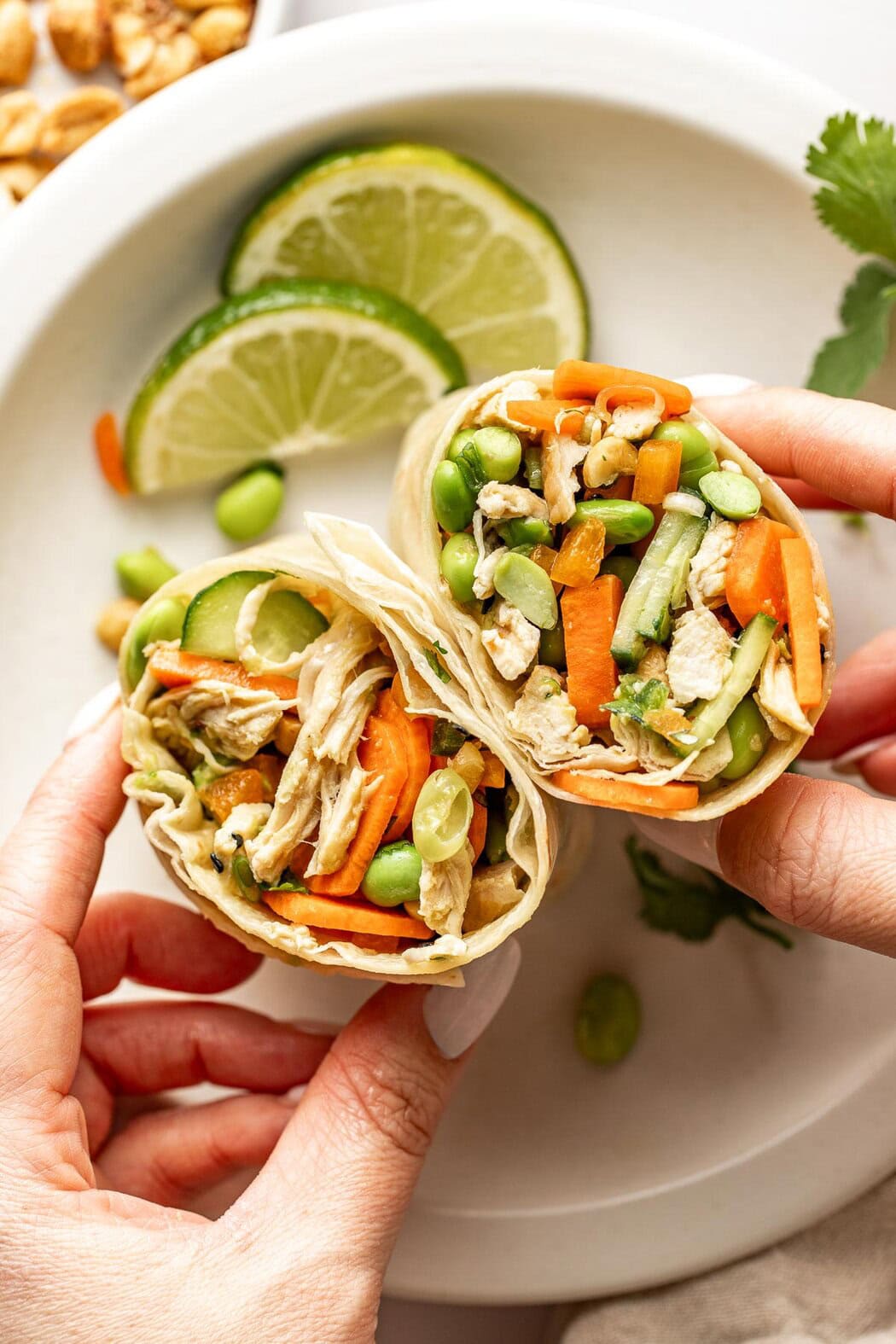 Close up view of a Thai chicken wrap cut in half showing the texture of the chicken and vegetables inside. 