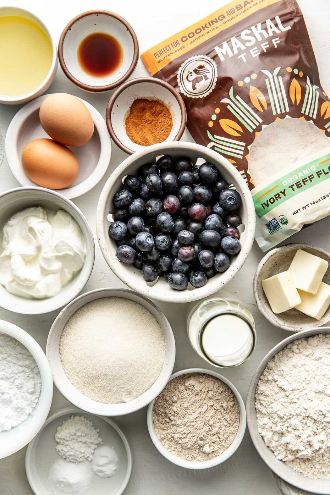Overhead view of a variety of ingredients for Blueberry Coffee Cake in different sized bowls. 