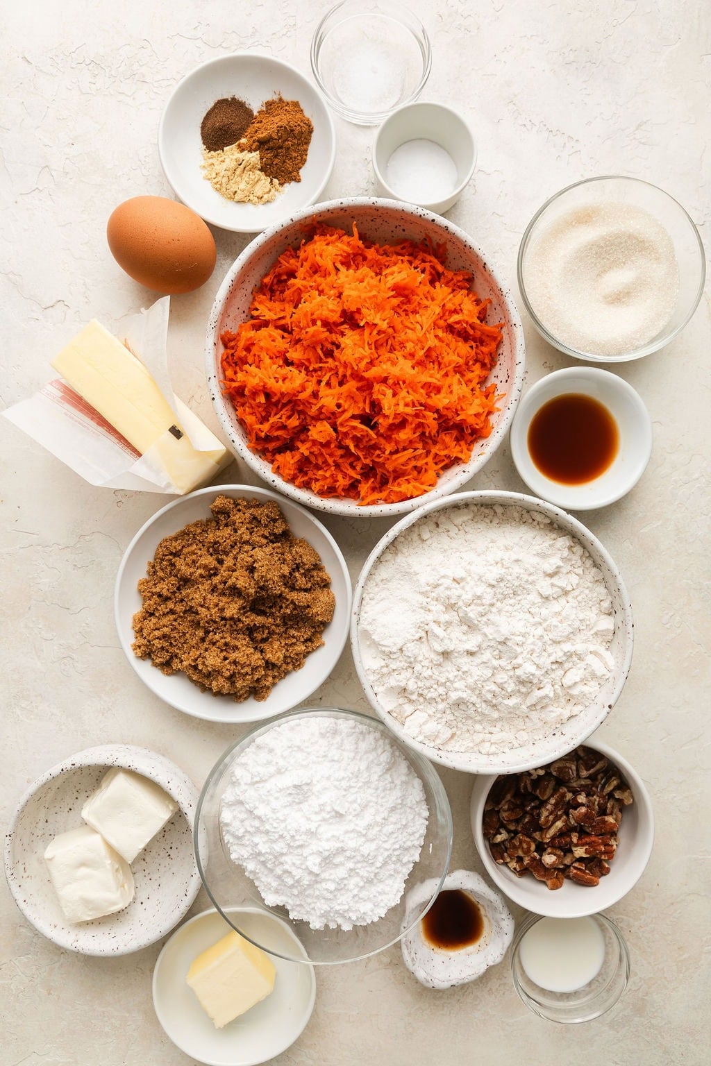 Overhead view of a variety of ingredients for carrot cake cookies in different sized bowls. 