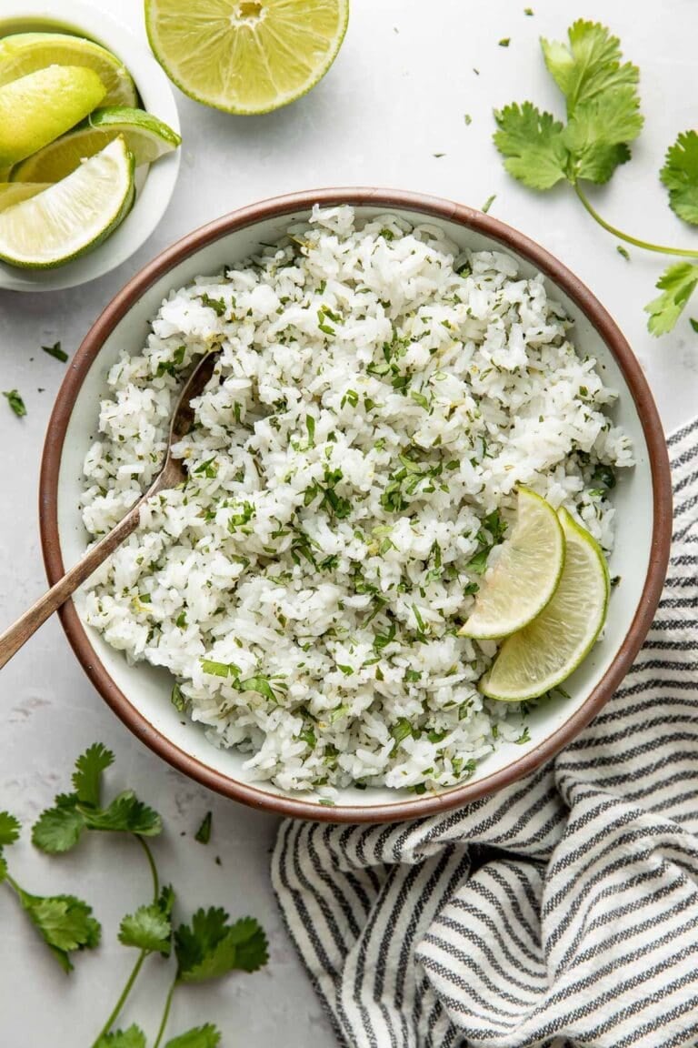 Overhead view of a bowl of cilantro lime rice garnished with lime wedges.