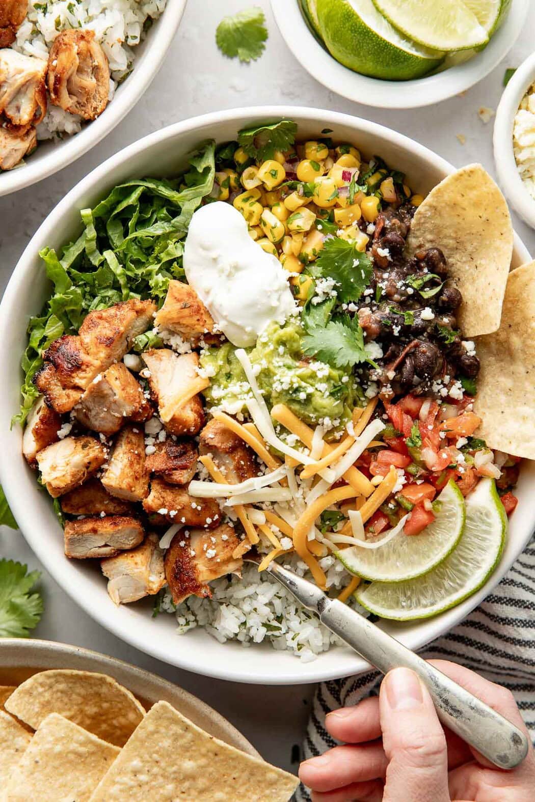 Overhead view of a chipotle chicken bowl filled with cilantro rice, corn salsa, black beans, and a dollop of guacamole.