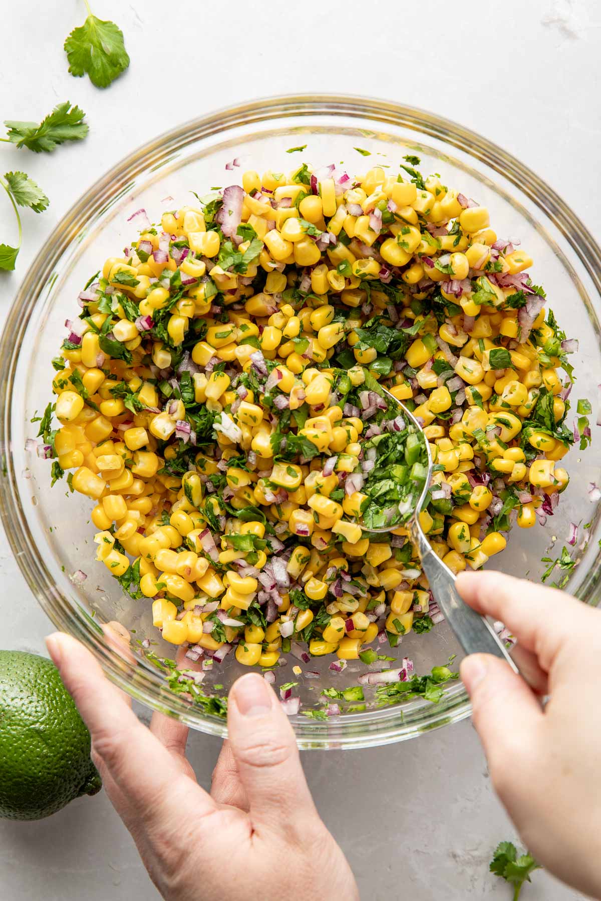 Overhead view of a glass bowl of freshly mixed Copycat Chipotle Corn Salsa.