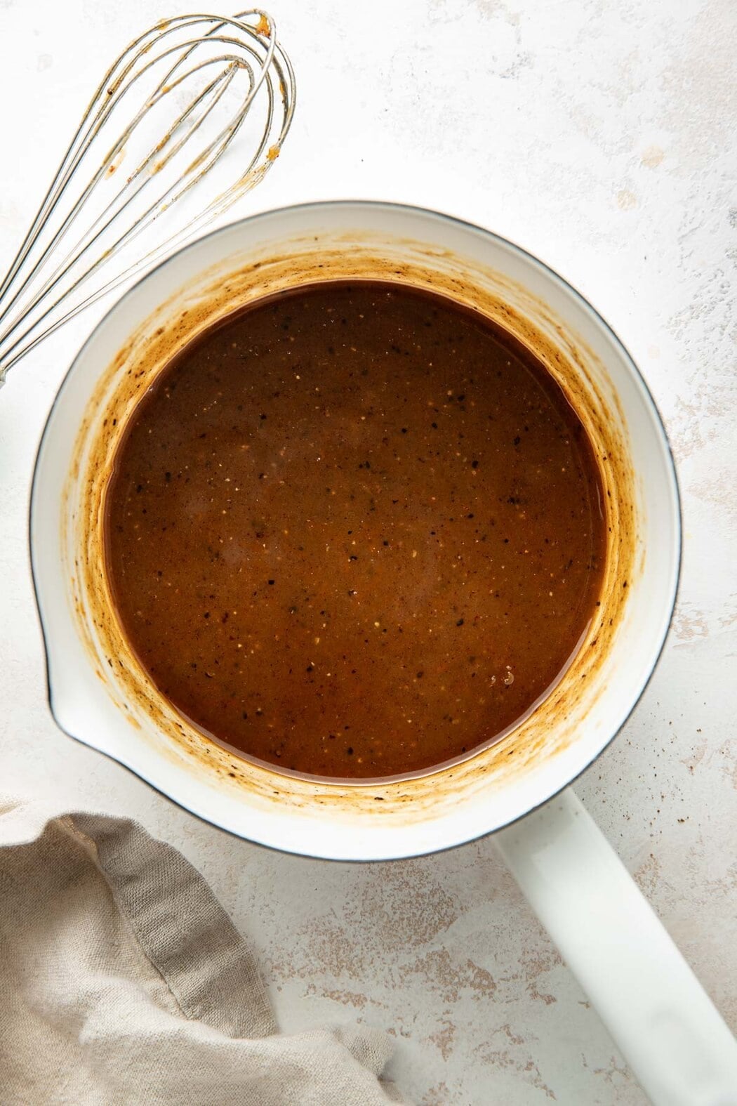 Overhead view of a saucepan filled with a thickened ham glaze.