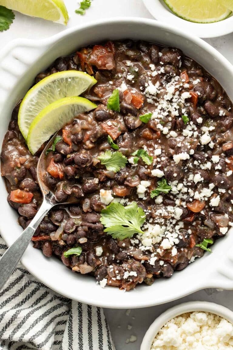 Overhead view of a bowl of Mexican black beans topped with fresh cilantro and sprinkled with cheese crumbles.