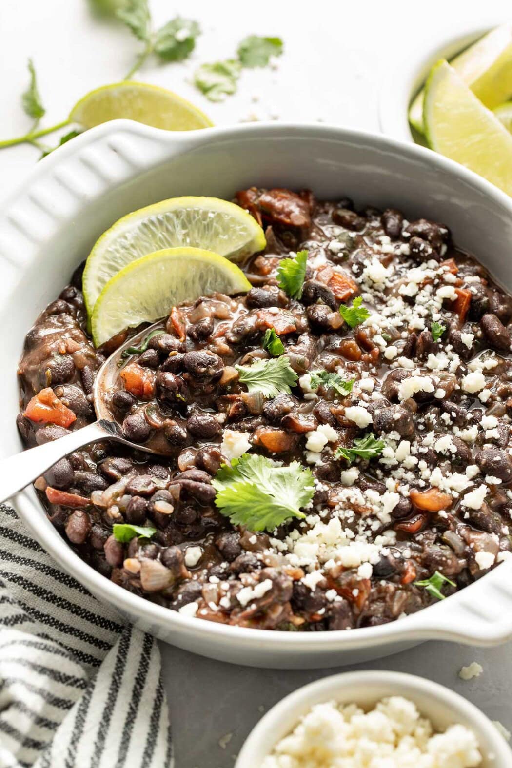 Close up view of a bowl of Mexican Black Beans topped with cheese crumbles and fresh cilantro.