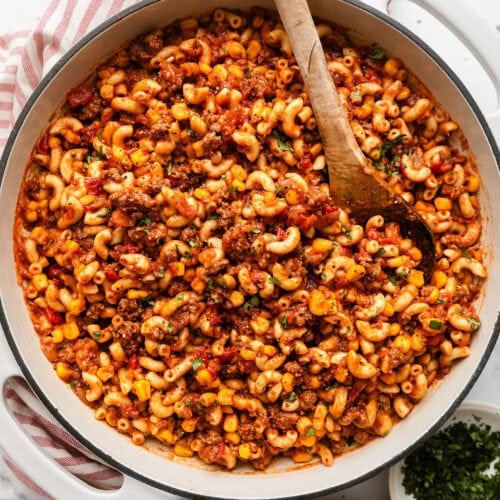 Overhead view of a skillet filled with goulash topped with fresh herbs.