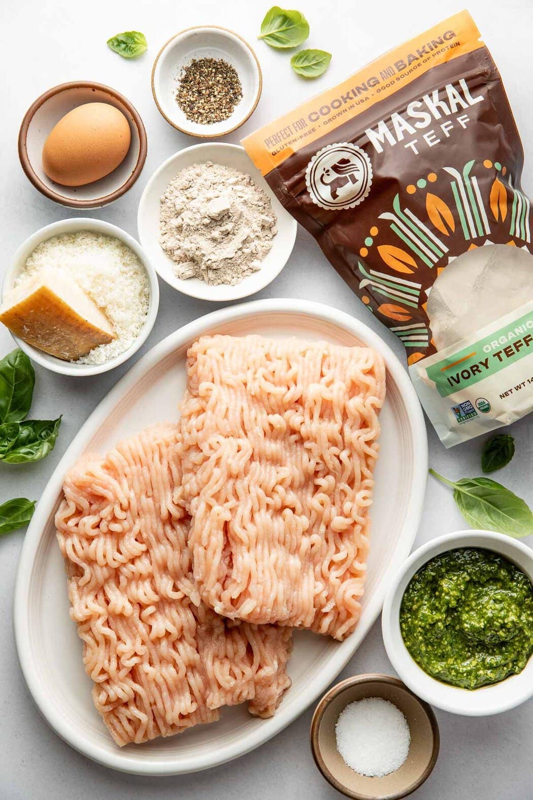 Overhead view of a variety of ingredients for Pesto Meatballs in different sized bowls. 