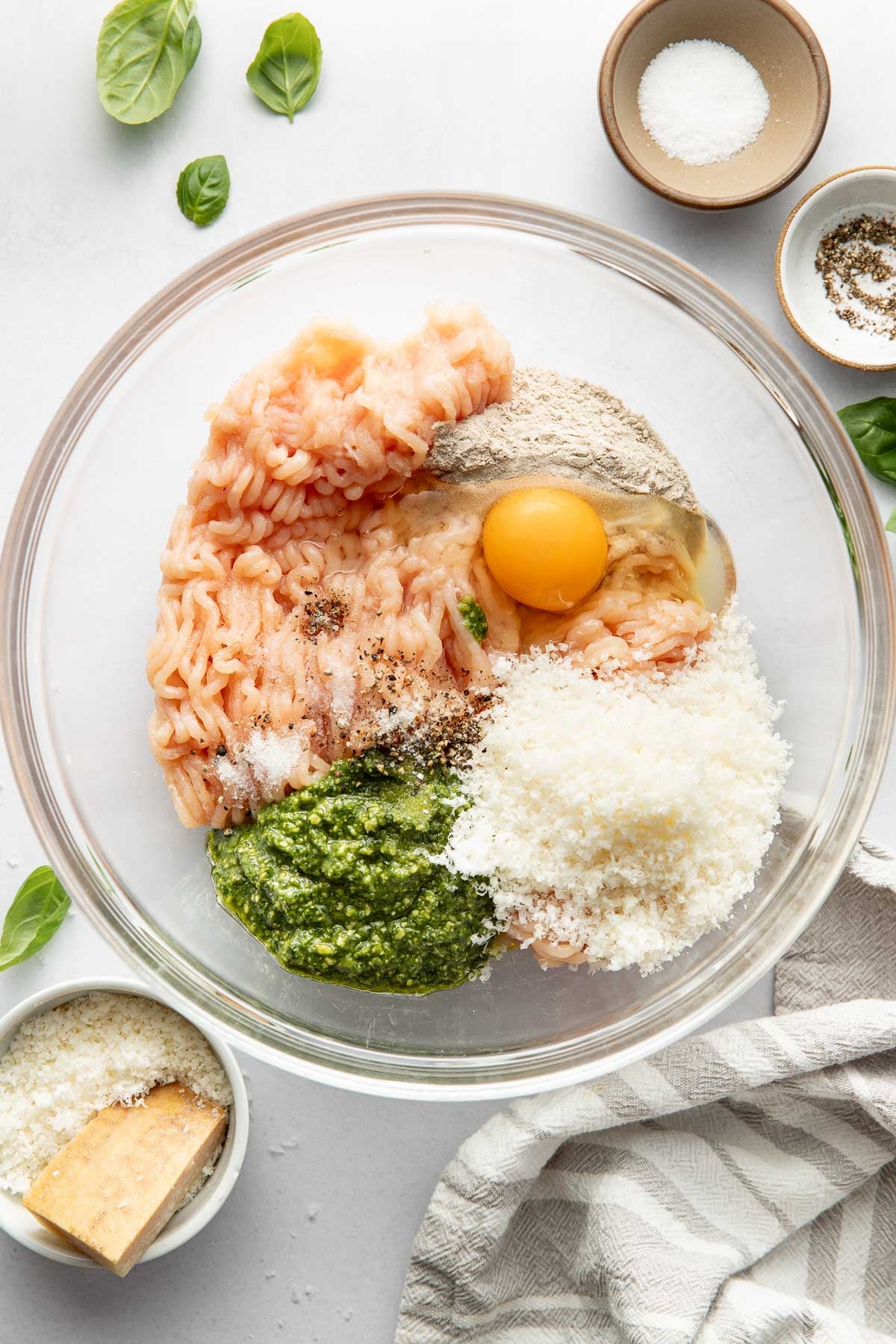 Overhead view of a glass bowl of Pesto Meatball ingredients ready for stirring. 