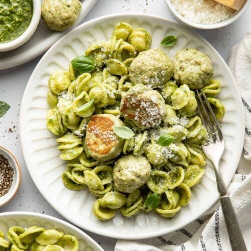 Overhead view of a plate filled with pasta and Pesto Meatballs topped with parmesan cheese.