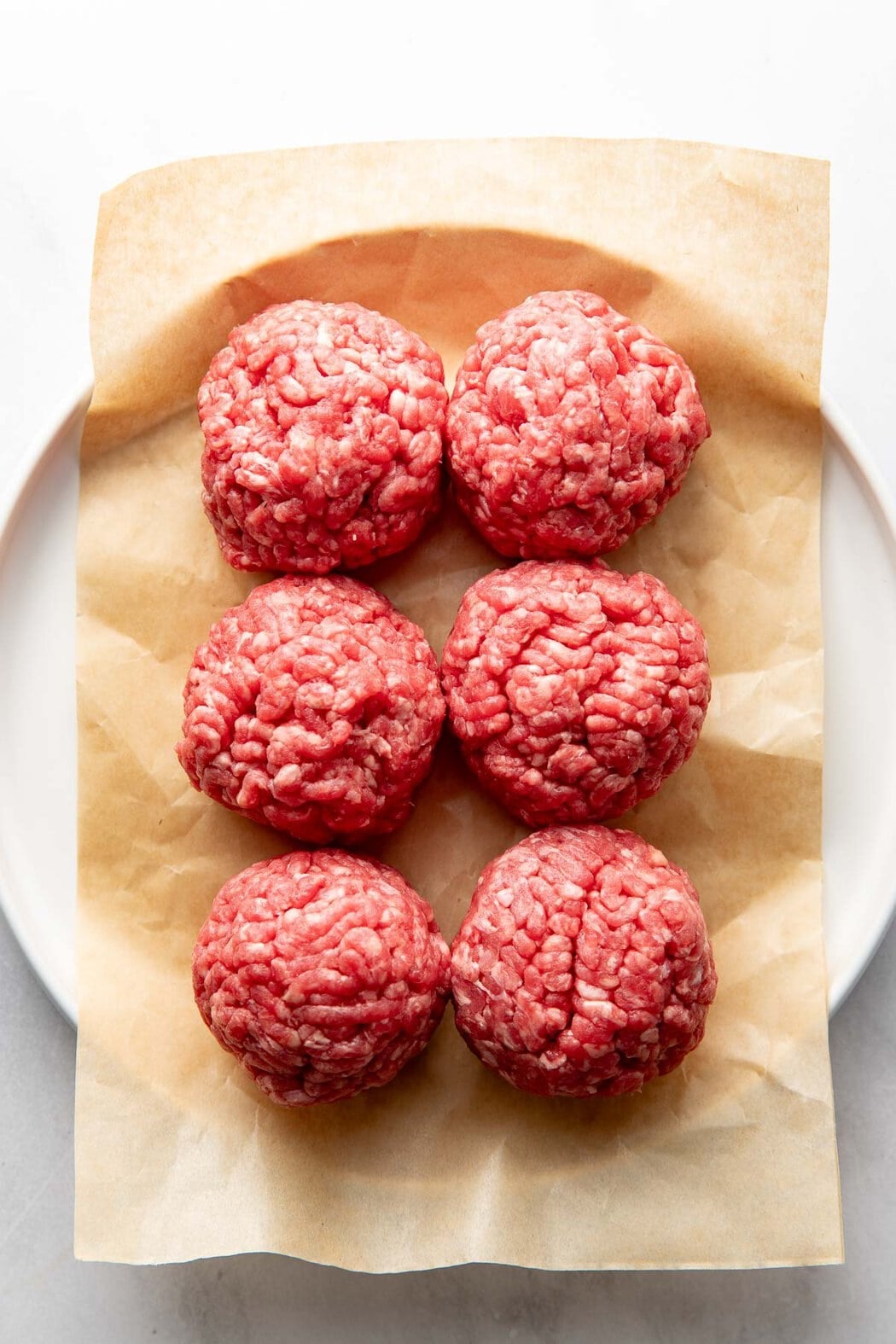 Overhead view of six balls of ground beef ready for cooking. 