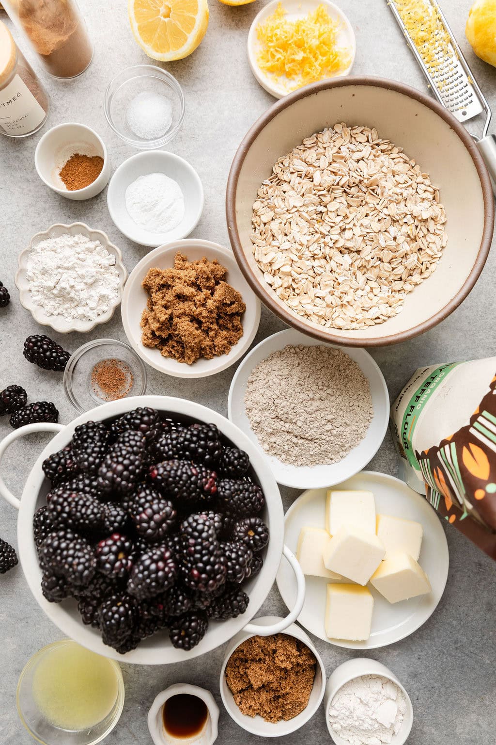 Overhead view of a variety of ingredients for Blackberry Crumble in different sized bowls.
