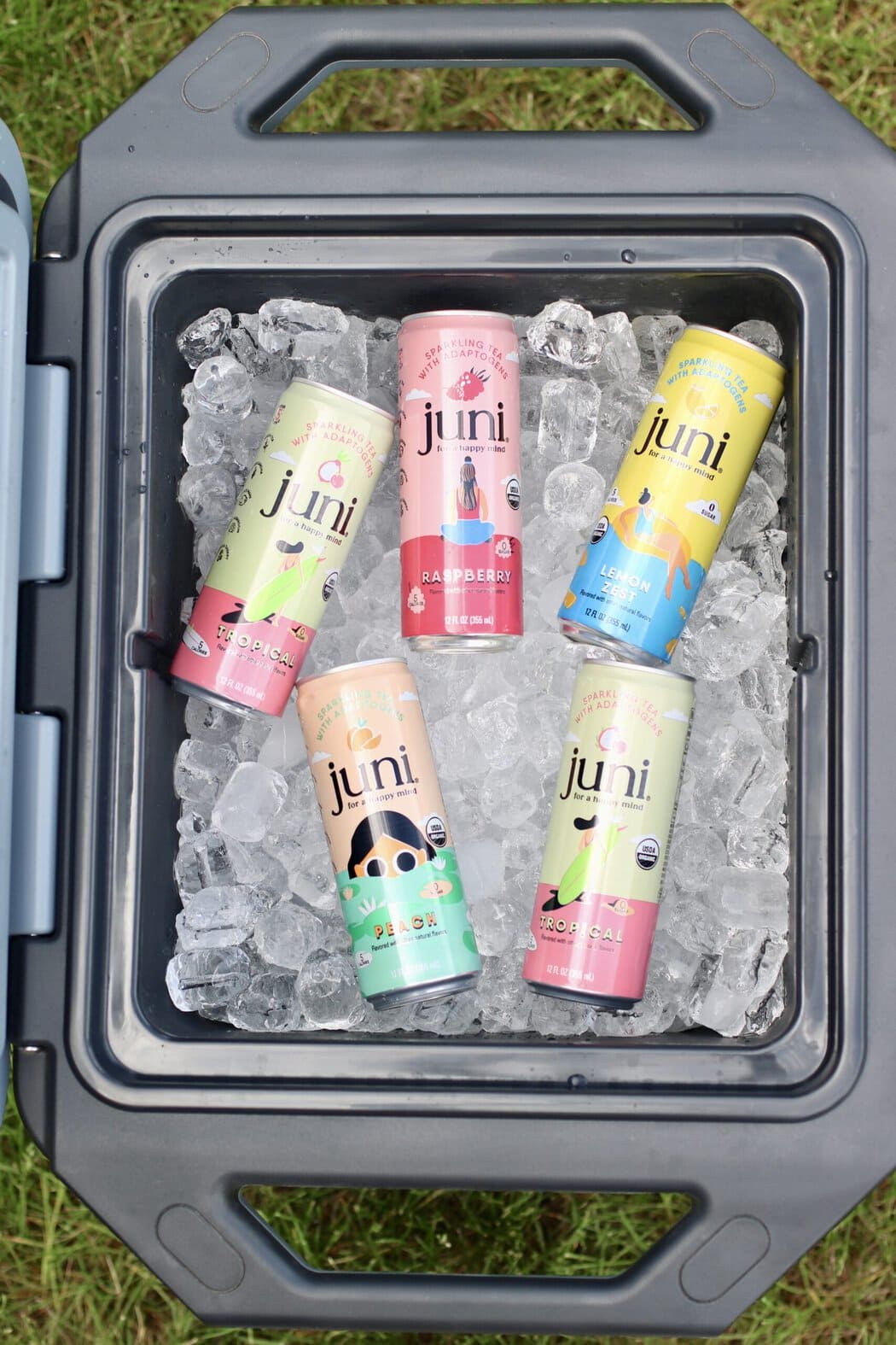 Overhead view of an open cooler filled with ice and canned juni mocktails.
