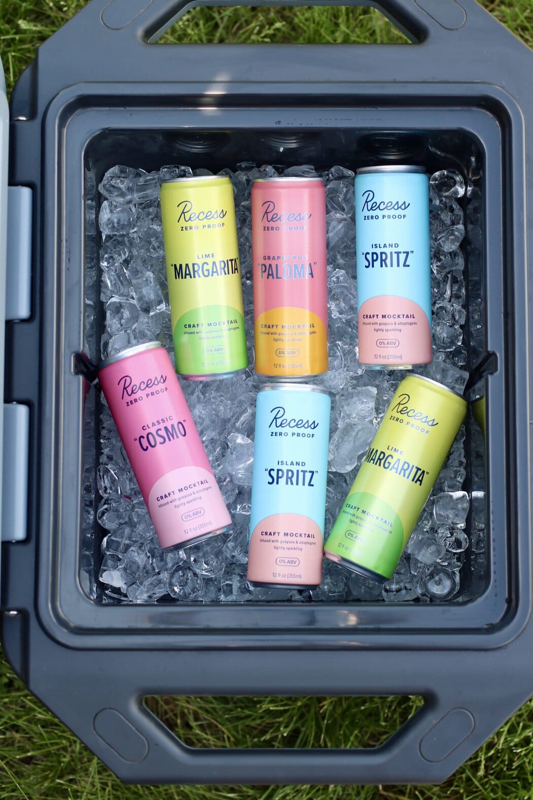 Overhead view of an open cooler full of ice and canned mocktails with colorful branding.