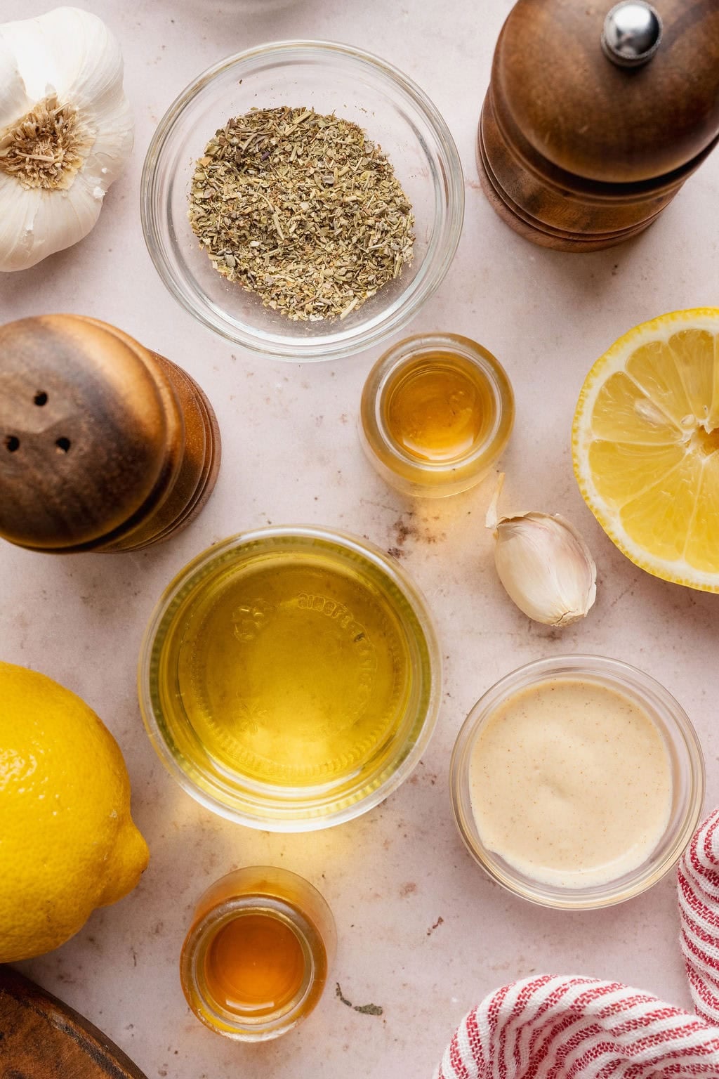 Overhead view of a variety of ingredients for Italian Dressing arranged on a white marble countertop.