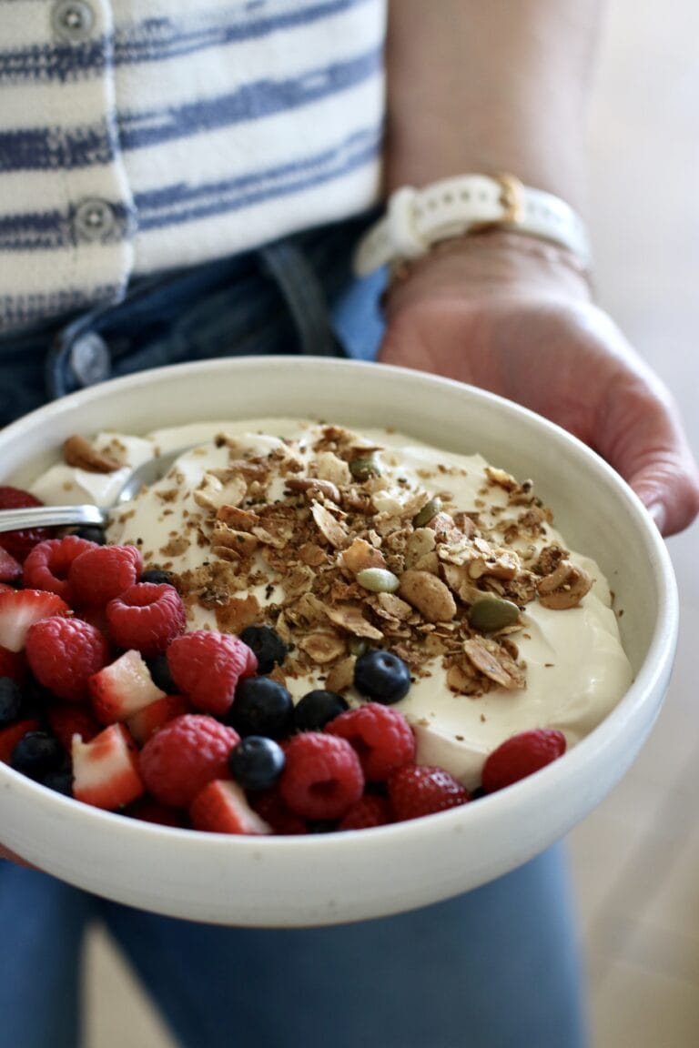 Close up view of a bowl of yogurt topped with fresh berries and granola. 
