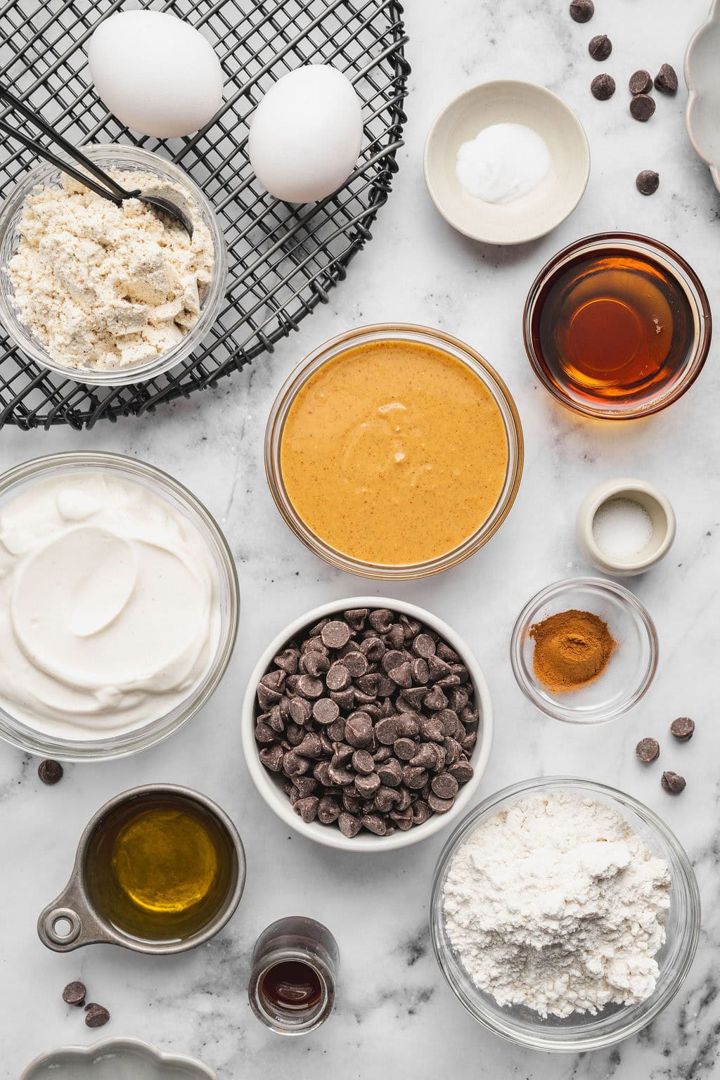 Overhead view of a variety of ingredients for Peanut Butter Protein Muffins in different sized bowls. 