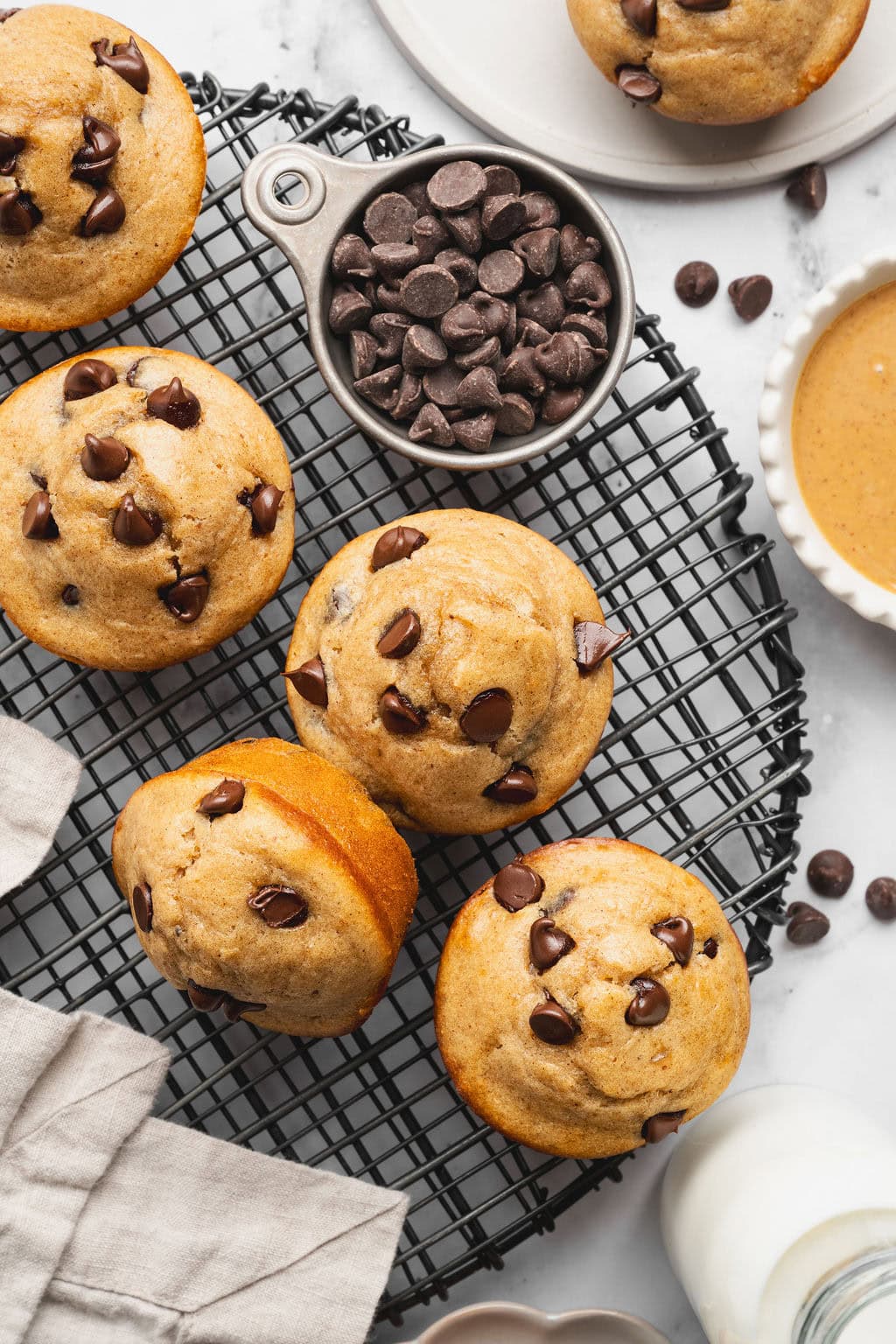 Overhead view of Peanut Butter Protein Muffins and chocolate chips on a wire cooling rack. 