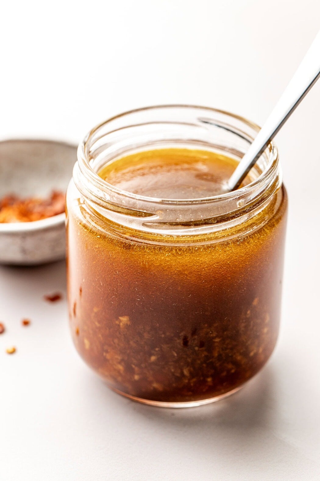 Close up view of a small glass jar of homemade dressing with an oil layer on top.