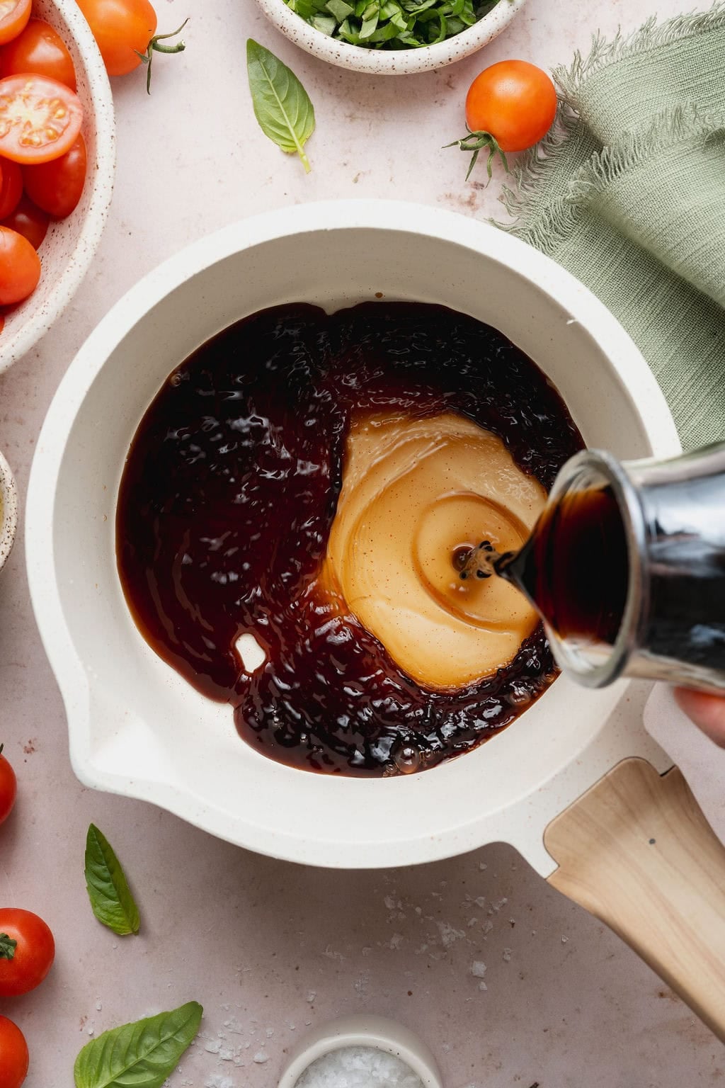 Balsamic glaze being poured from a bottle into a small saucepan. 