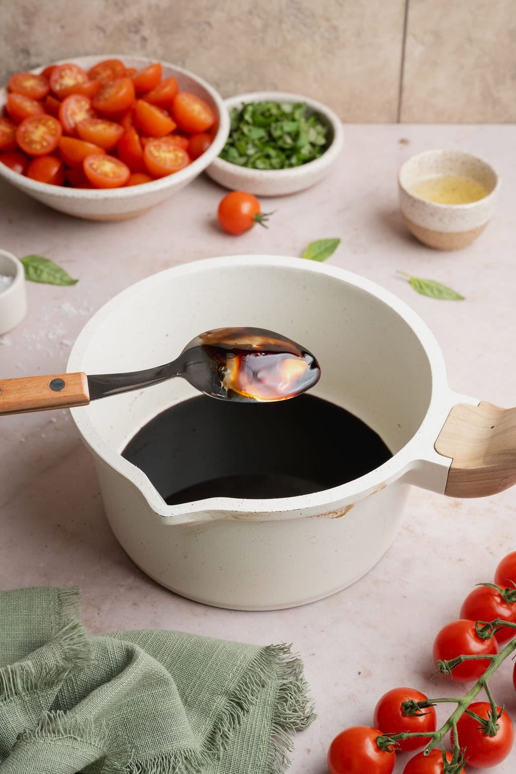 Balsamic glaze coating the back of a spoon held over a pot of balsamic glaze. 