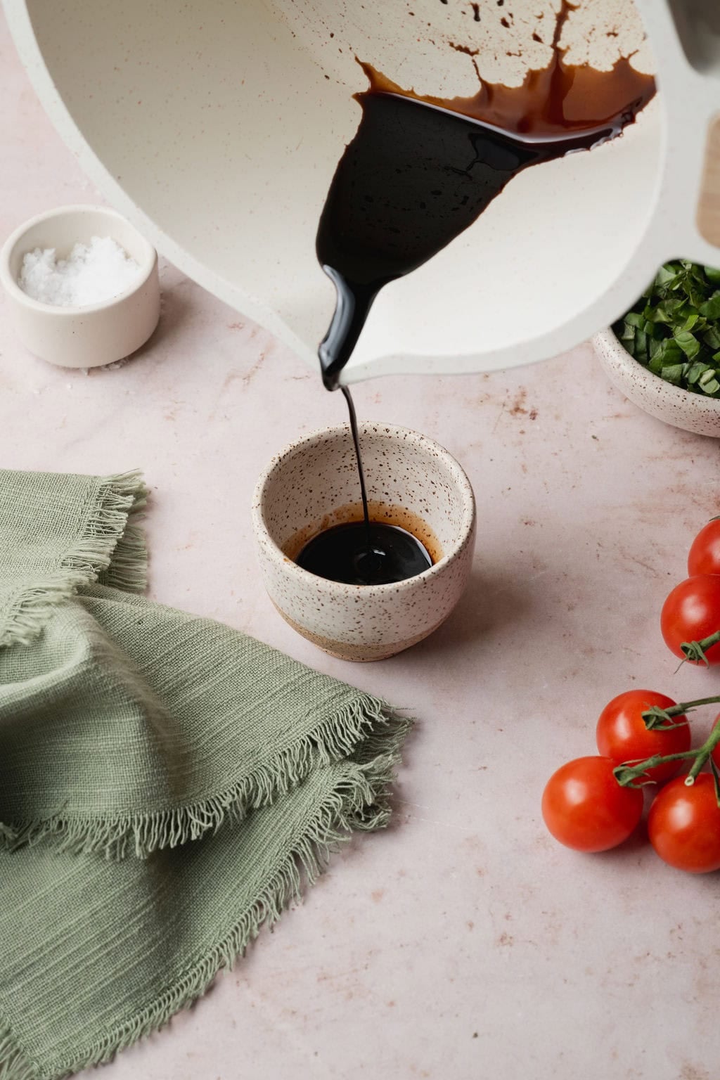A pot of balsamic glaze being poured into a small bowl. 