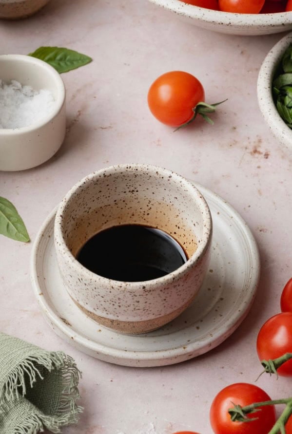 A small white speckled bowl of balsamic glaze.