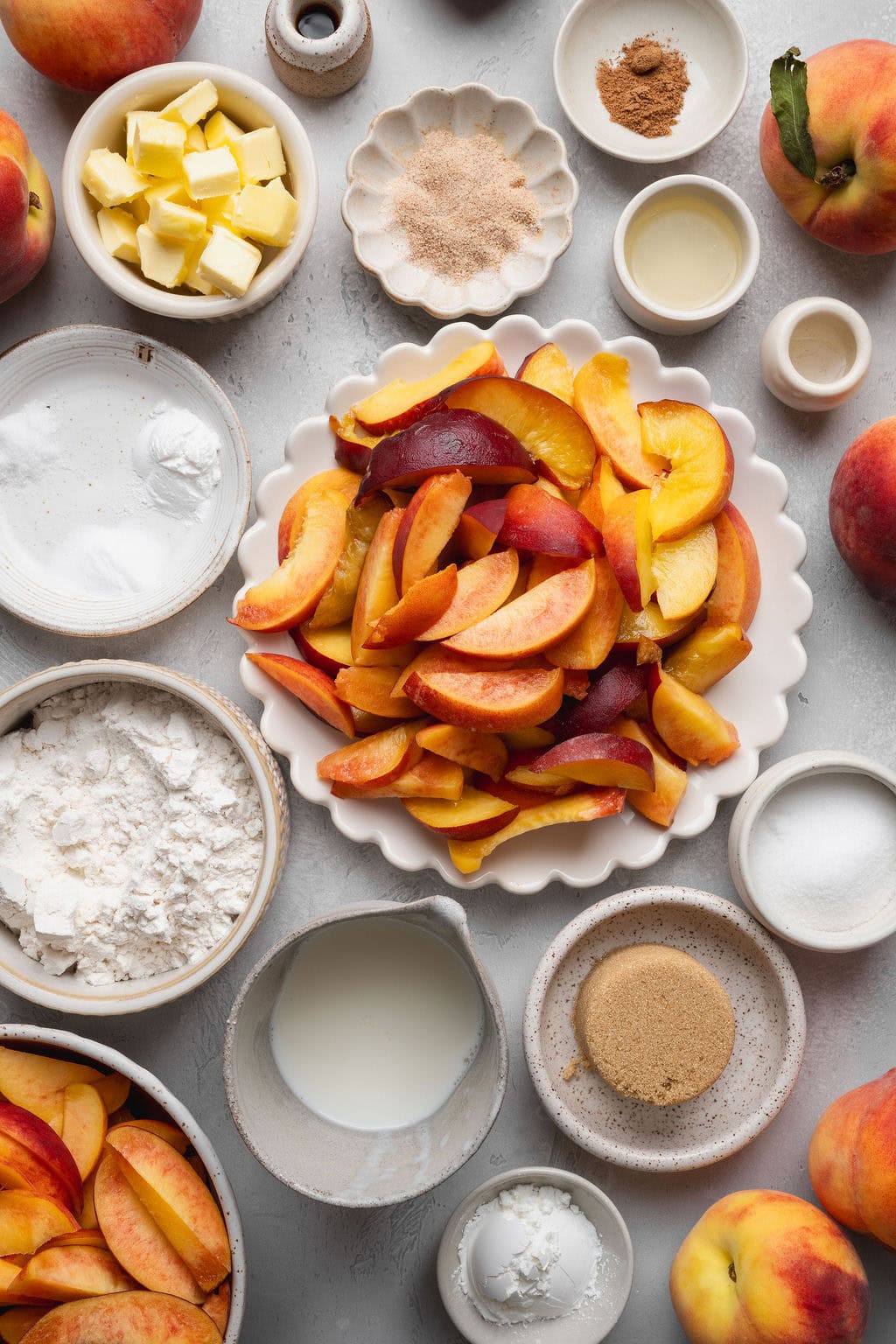 Bowls and plates of wet and dry ingredients to make a homemade peach cobbler recipe.